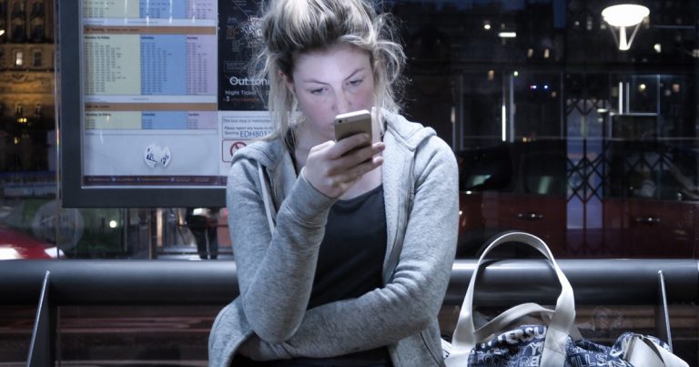 tired looking consumer staring at smartphone
