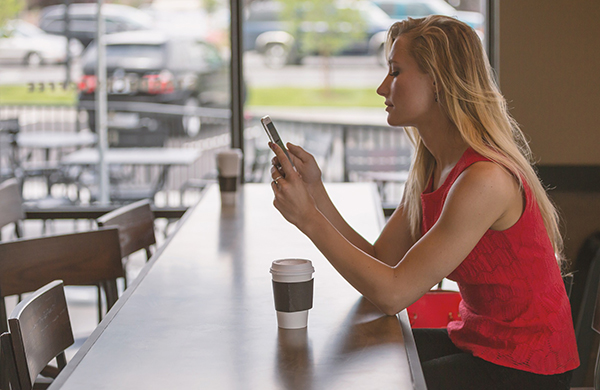 woman using smartphone at coffee shop table