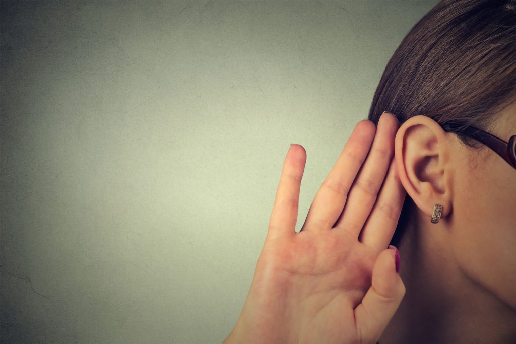 woman with hand behind ear listening to voice of customer